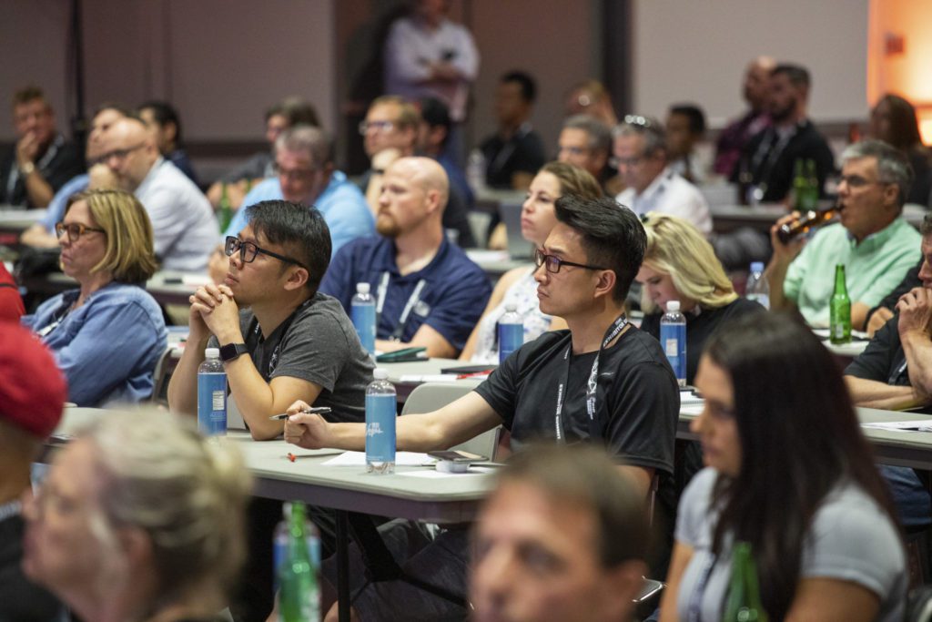 People sitting at tables learning at a conference.