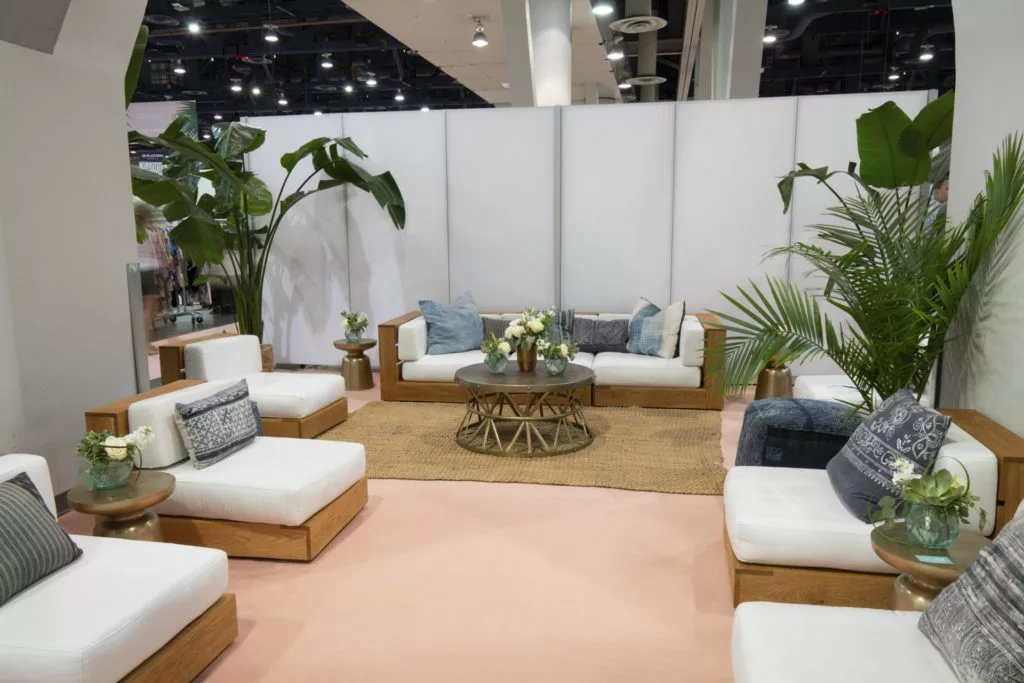 White couch and chairs in a private setting with plants and flowers in the room.