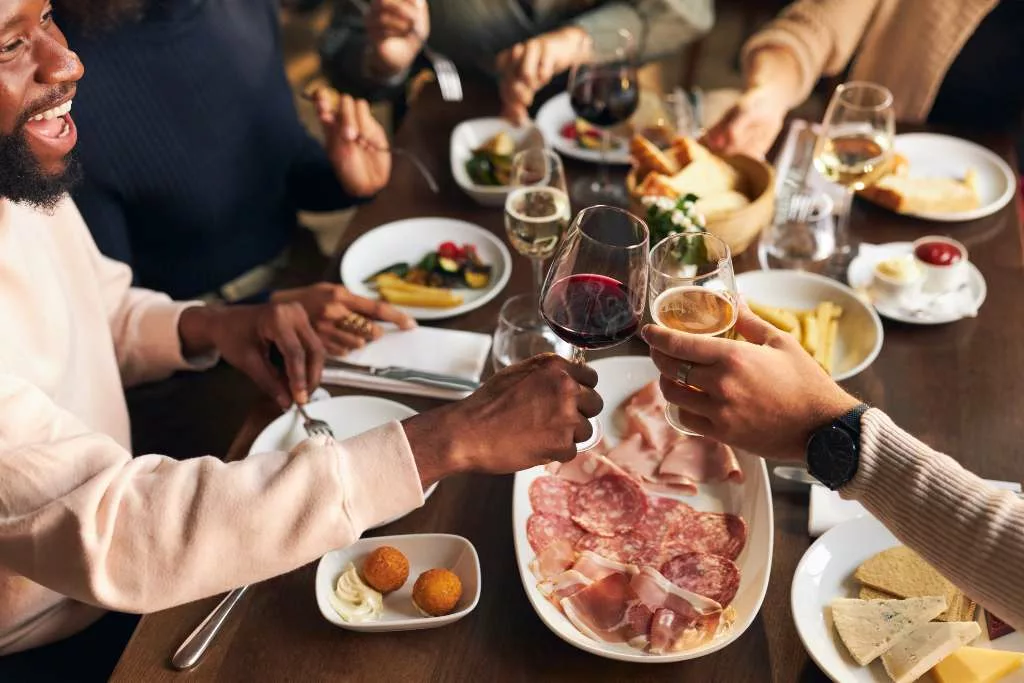 People toasting with drinks in hand at a dinner table.