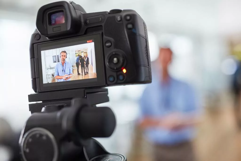 Video camera capturing video of a man standing in his office.