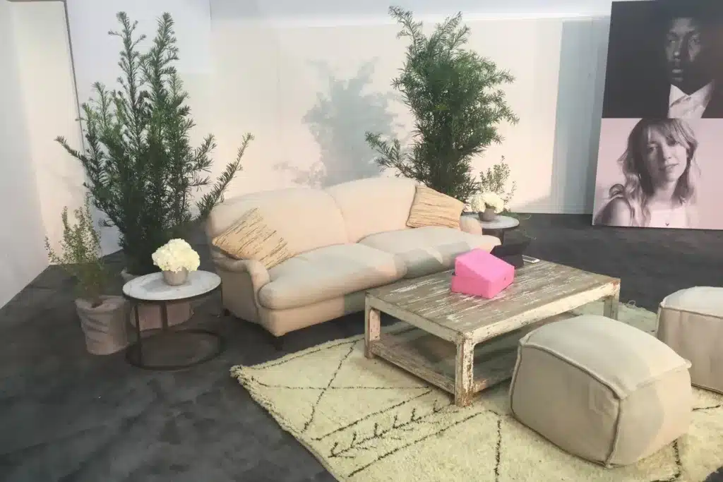 Comfortable seating area with plants and decor at a trade show.