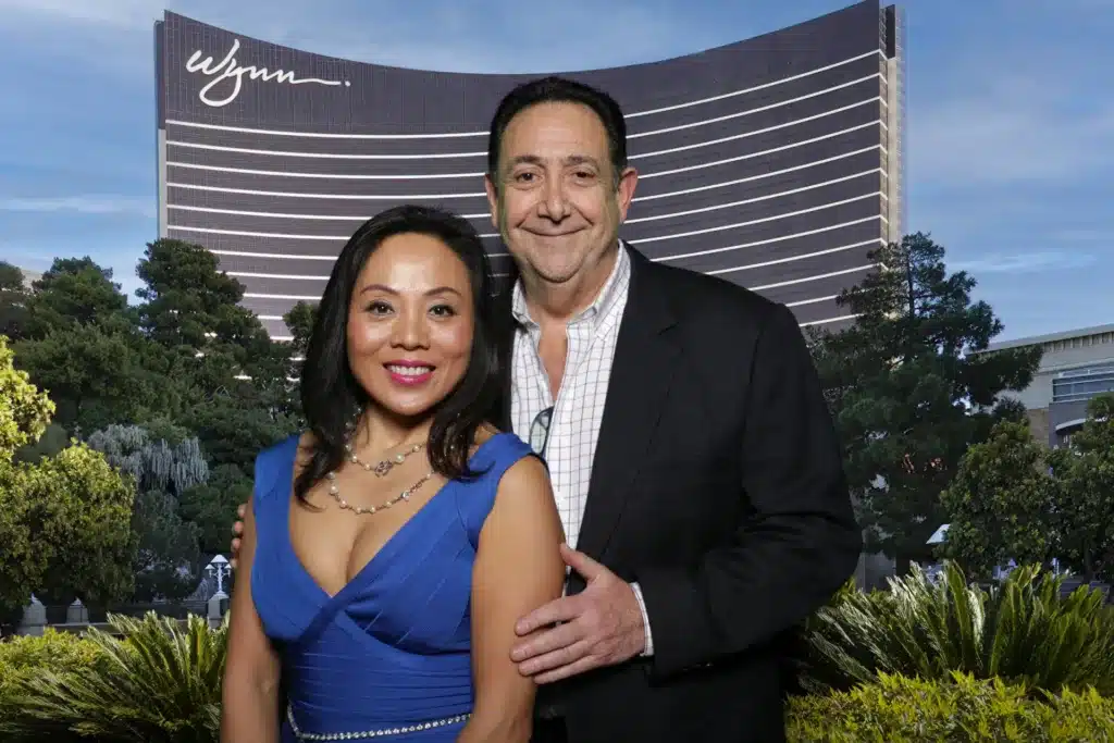Man and woman posing in front of a green screen image of the Wynn in Las Vegas, Nevada.
