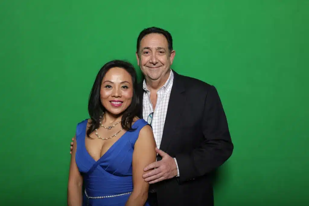 Man and woman posing in front of a green screen.