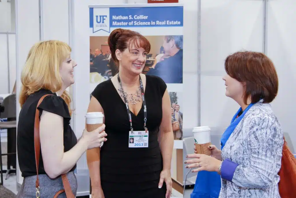 Three women at talking together at a trade show booth.