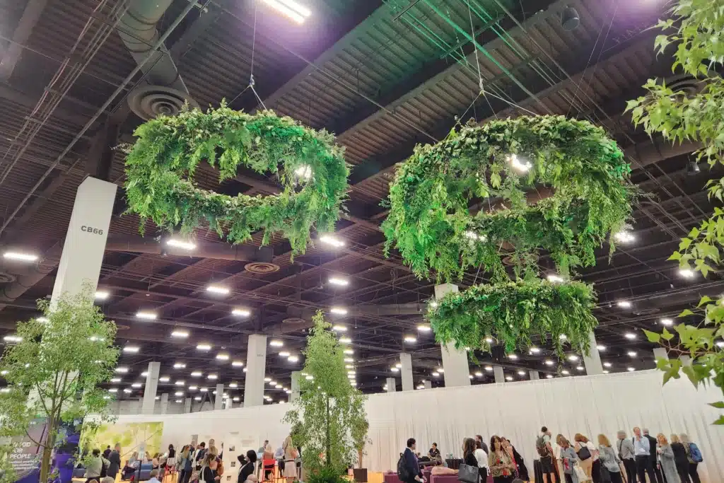 Floral and greenery rings suspended from the ceiling at a trade show exhibit. 