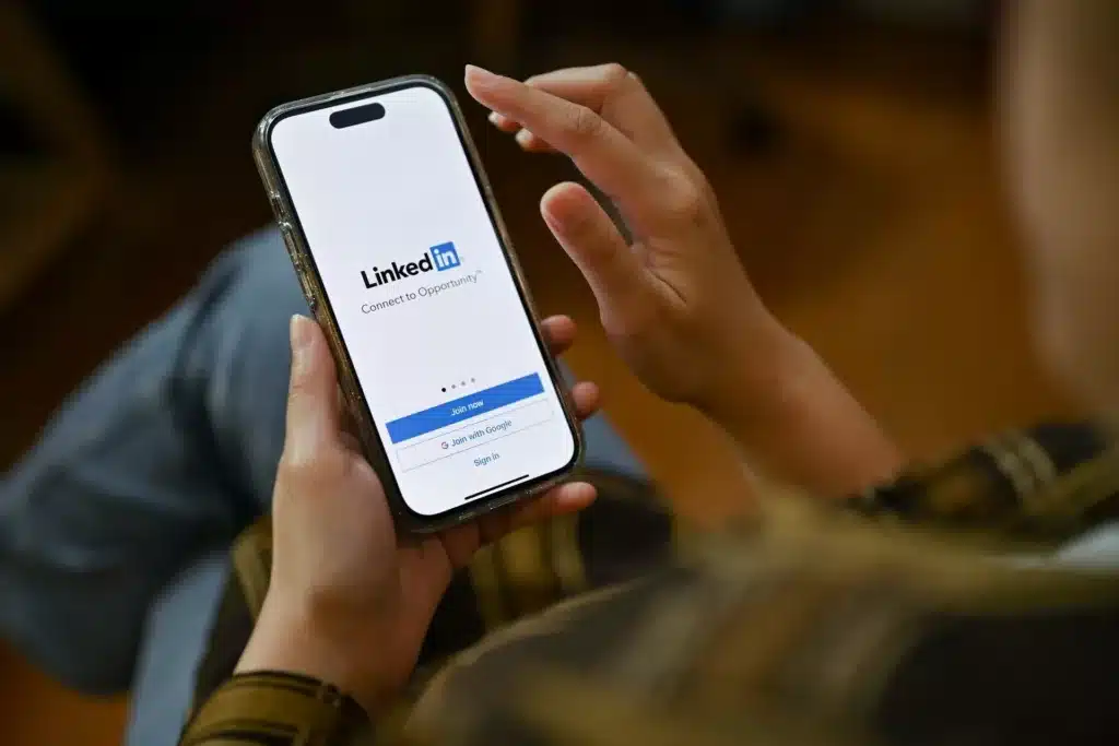 Person holding a cell phone with "LinkedIn" website on the screen.