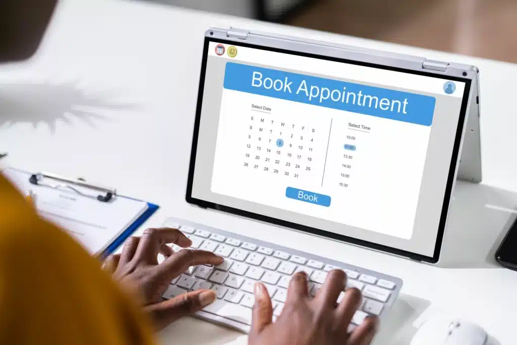 Person typing on a laptop computer with the text 'book appointment' on the screen.