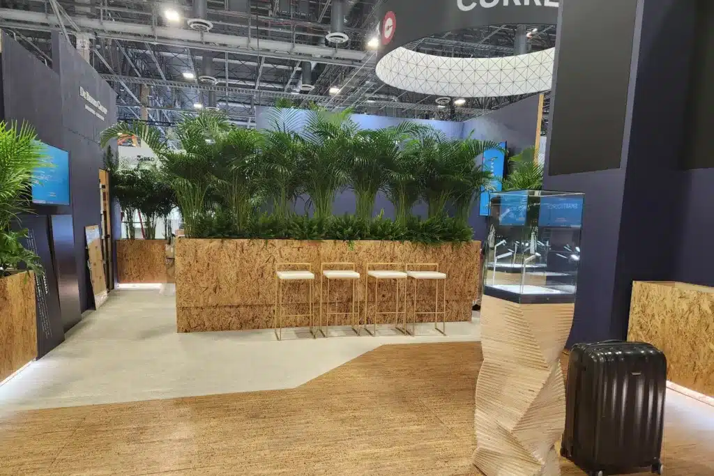 Tall cork container with large live plants at a trade show booth.