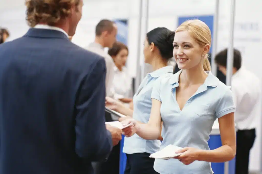 woman handing a man a piece of paper at a trade show