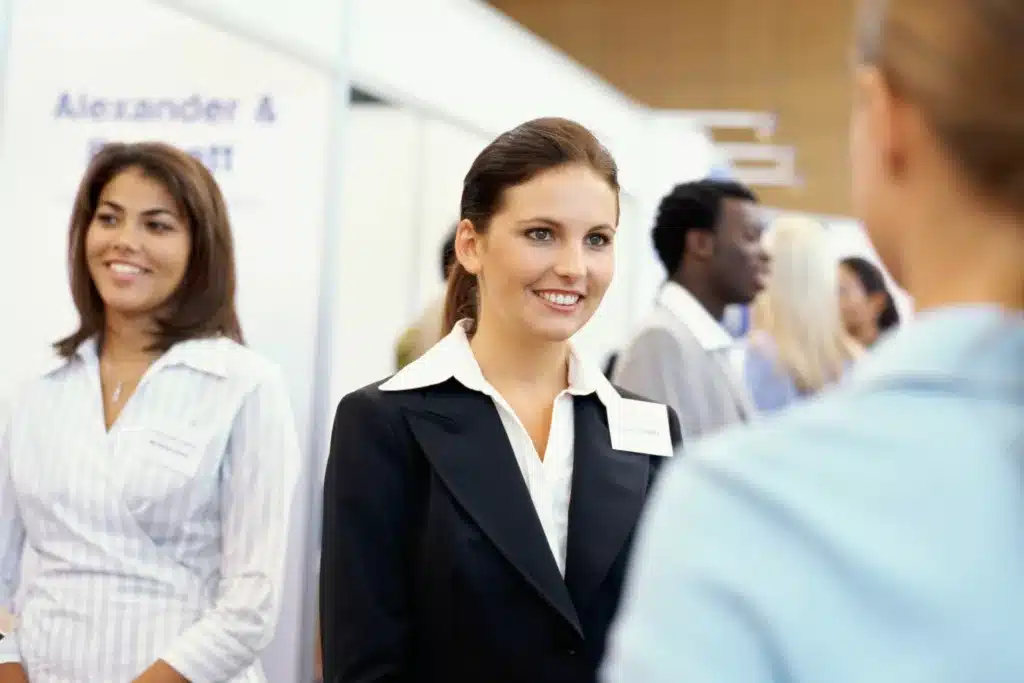 four people dressed in business attire smiling at each other