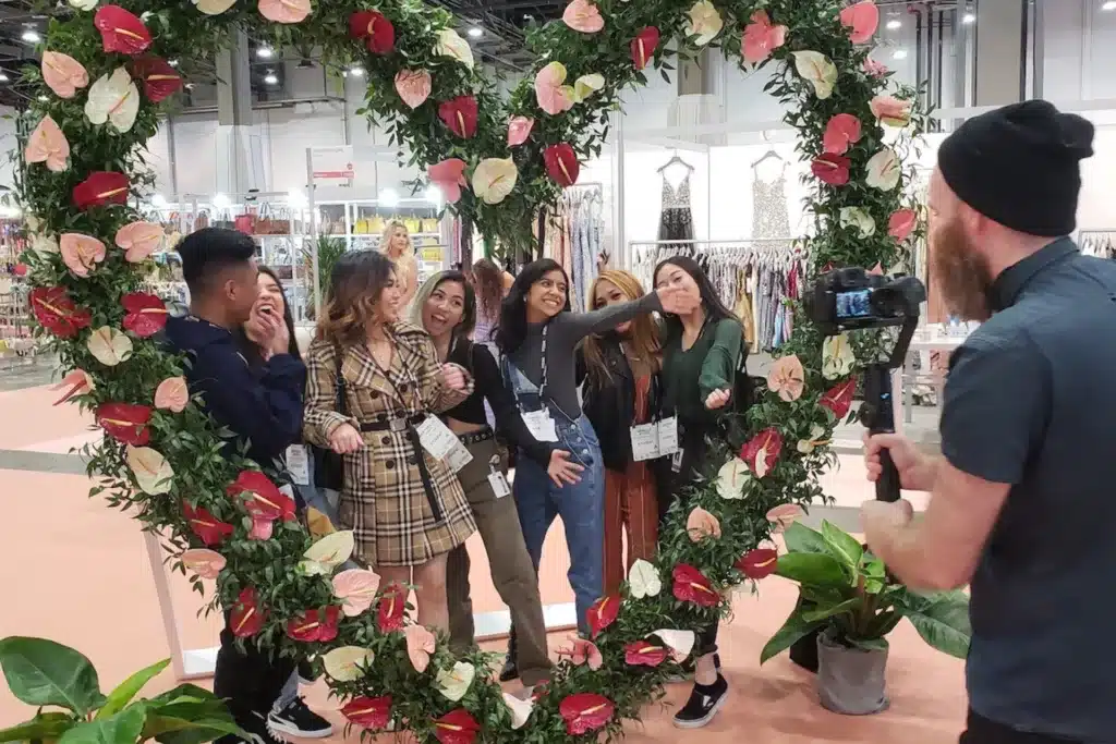 group of people posing behind a heart shaped floral structure while their photo is being taken.
