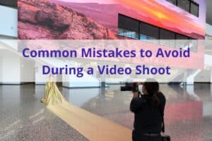 Photo of a person holding a video camera filming a woman in a gown, the text "Common Mistakes to Avoid During a Video Shoot" in the foreground.